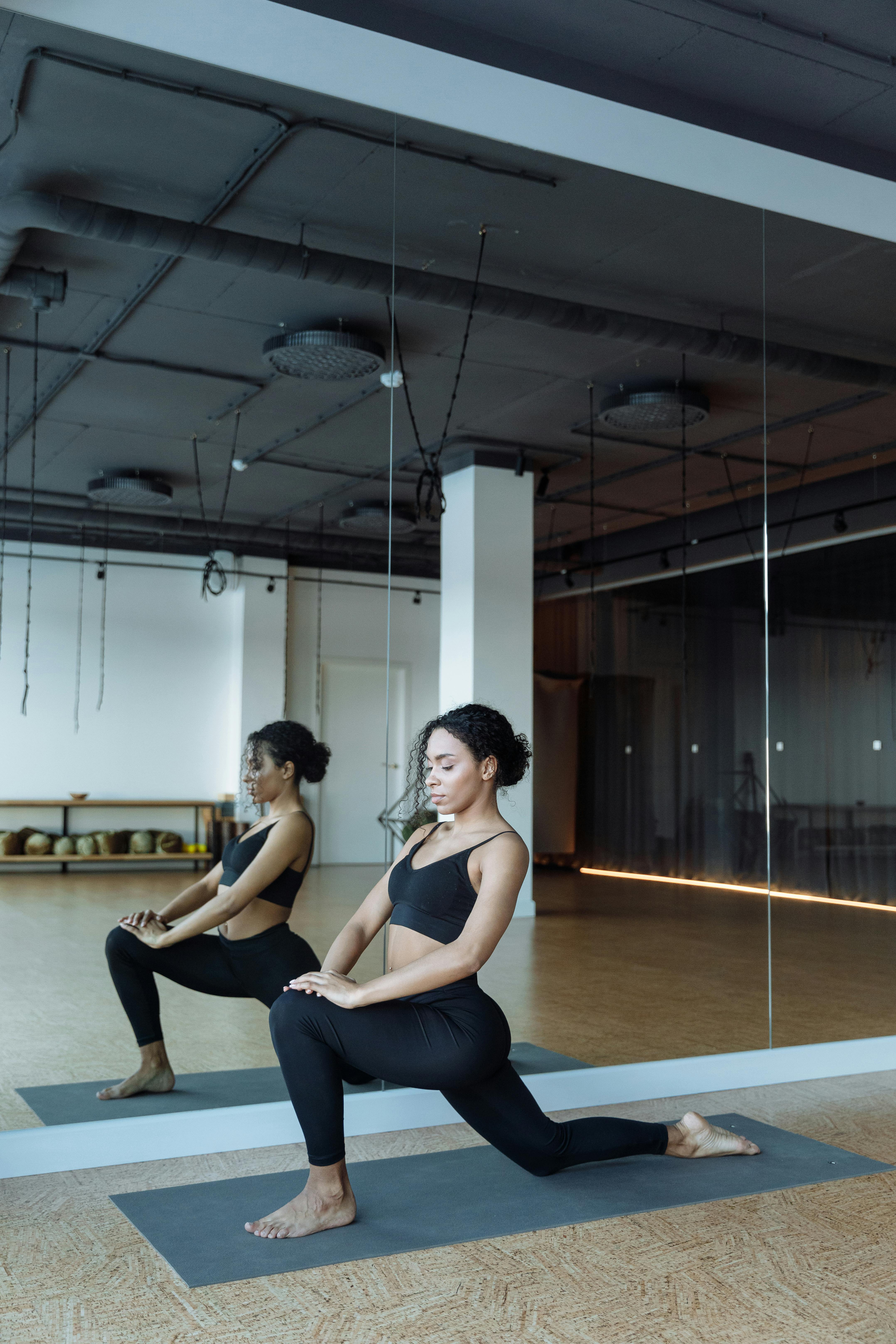 Woman in Black Tank Top and Blue Denim Jeans Sitting on Black Chair