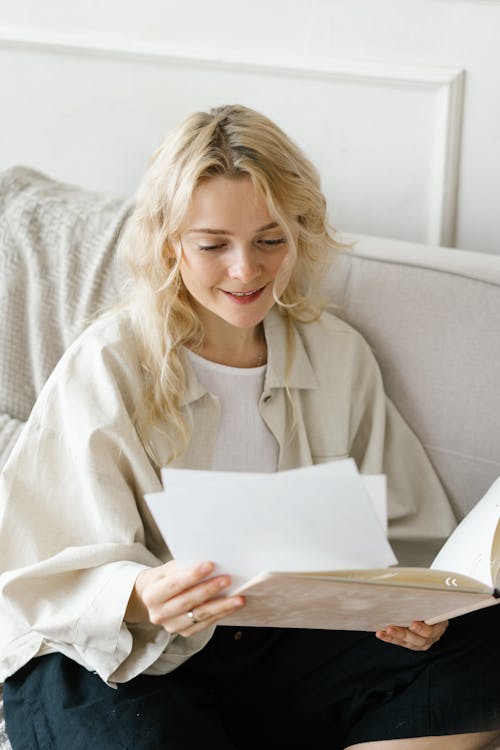 Gentle woman with fair hair reading papers in folder