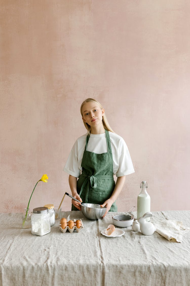 Woman With Metal Bowl At Table With Milk And Eggs