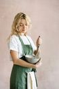 Woman in apron preparing food against light background