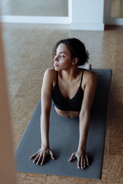 Free African American woman performing yoga indoors on a mat, focusing on flexibility and relaxation. Stock Photo