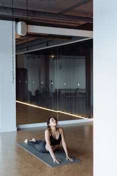 Focused woman in yoga pose on mat in serene studio with mirror reflection.