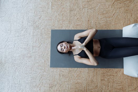 Top view of a woman meditating on a yoga mat indoors, embracing mindfulness and relaxation.