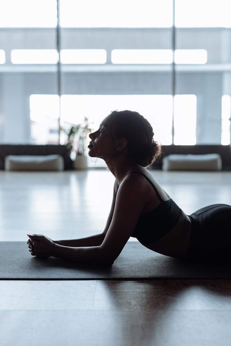 Woman In Black Sports Bra Lying On A Yoga Mat While Meditating