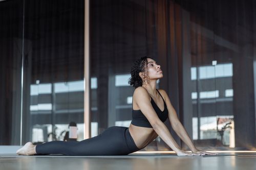 Free A young woman doing a yoga pose in a modern studio, promoting wellness and relaxation. Stock Photo