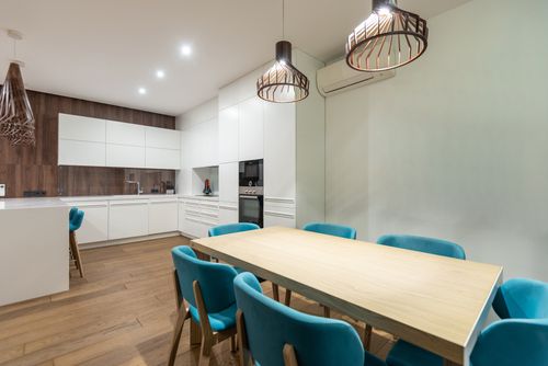 Free Set of turquoise chairs at table placed in stylish spacious kitchen with white cupboards and modern light kitchenware at home Stock Photo