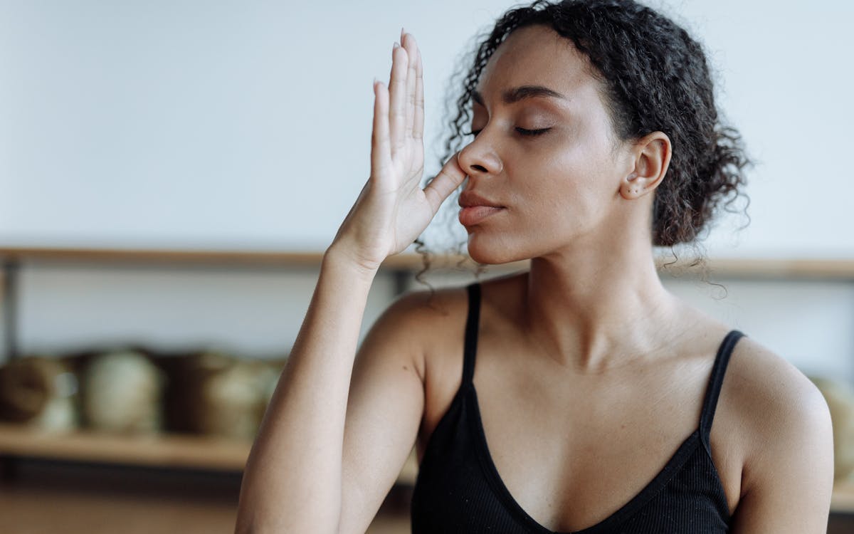 Close-up of a woman practicing yoga breathing techniques indoors, focusing on relaxation.