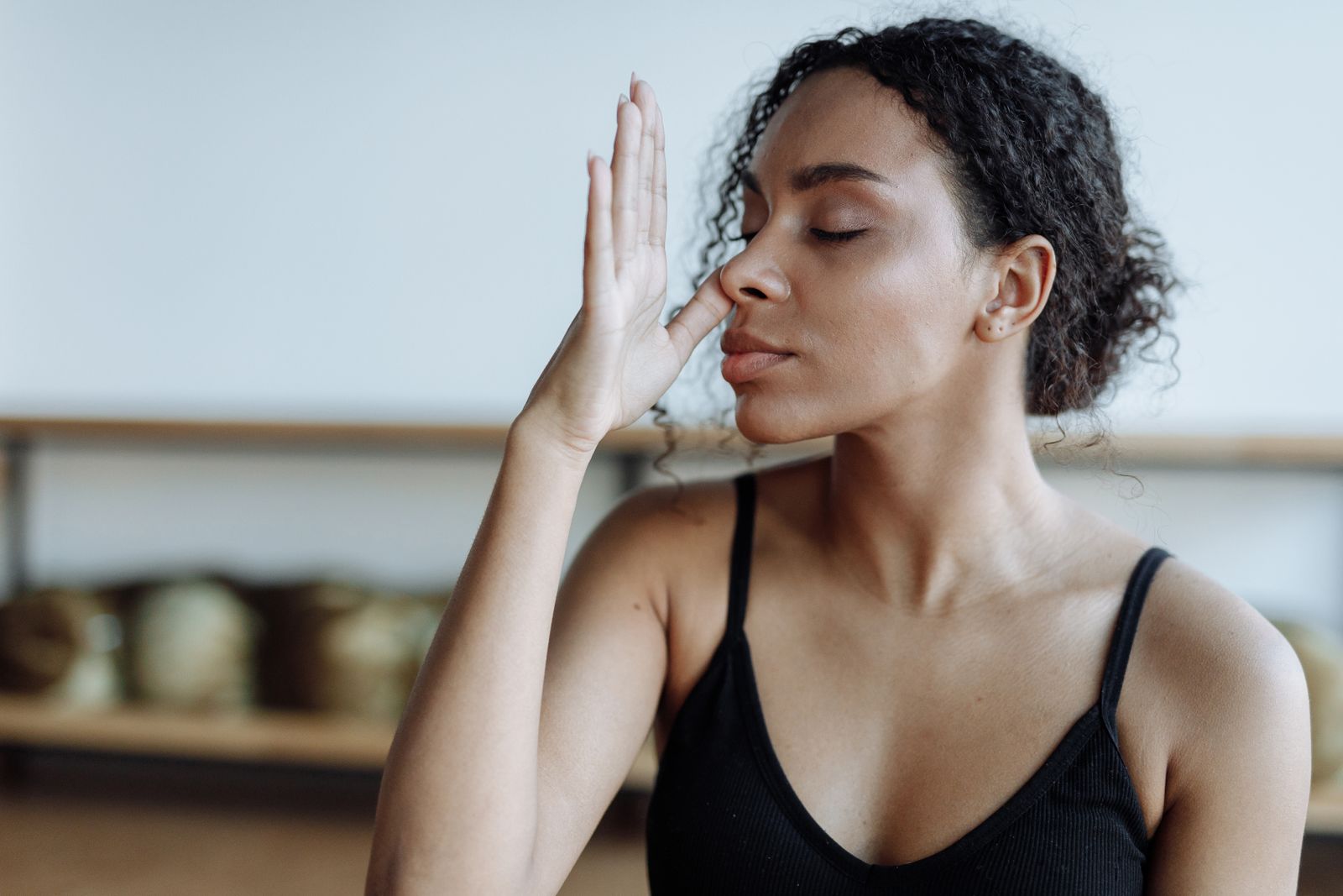 Woman sitting cross-legged practicing pranayama breathing exercises in a bright room