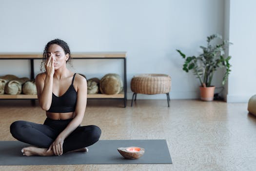 Tranquil scene of a woman meditating indoors on a yoga mat with a candle for relaxation.