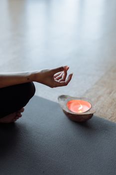 Serene meditation setup with a hand mudra and glowing candlelight for a calming yoga experience.