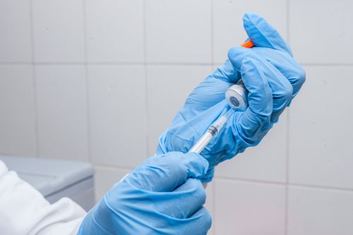 Free Close-up of hands in gloves preparing a vaccine syringe indoors. Stock Photo