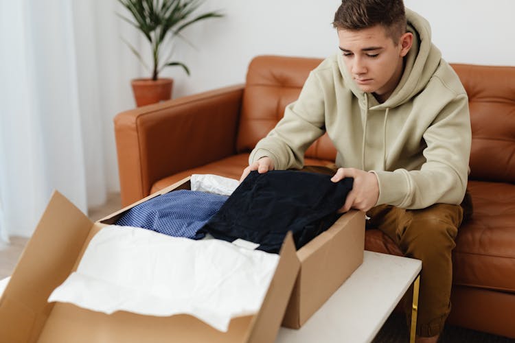 Man Wearing Hoodie Unboxing Clothes 