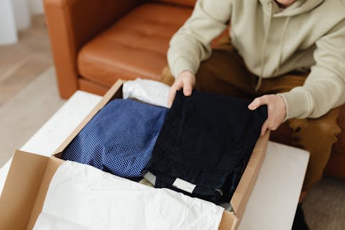 Free Person Holding Clothing From Cardboard Box Stock Photo