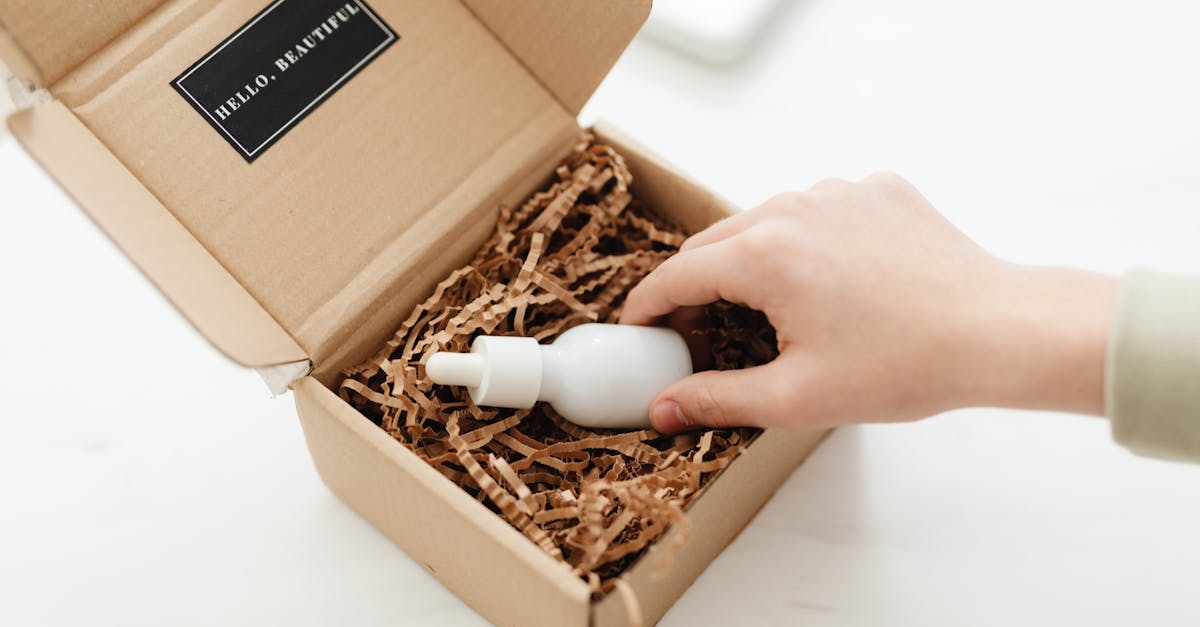 A hand unboxes a beauty product in a sustainable cardboard package with shredded paper. A hand unboxes a beauty product in a sustainable cardboard package with shredded paper.