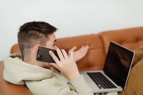 Free A Man Talking on the Phone while Sitting on the Couch Stock Photo