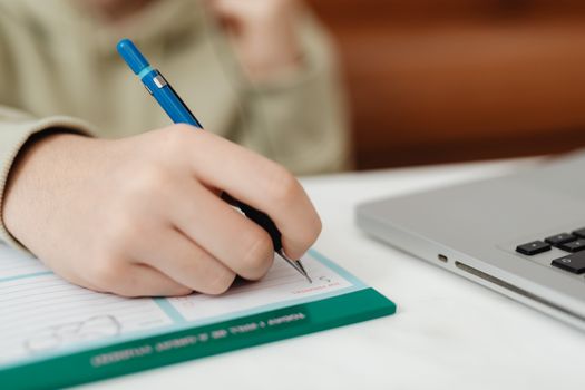 A Hand Filling Up the Form Beside the Laptop