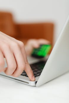 Close-up of a finger pressing the power button on a laptop, indicating technology interaction.