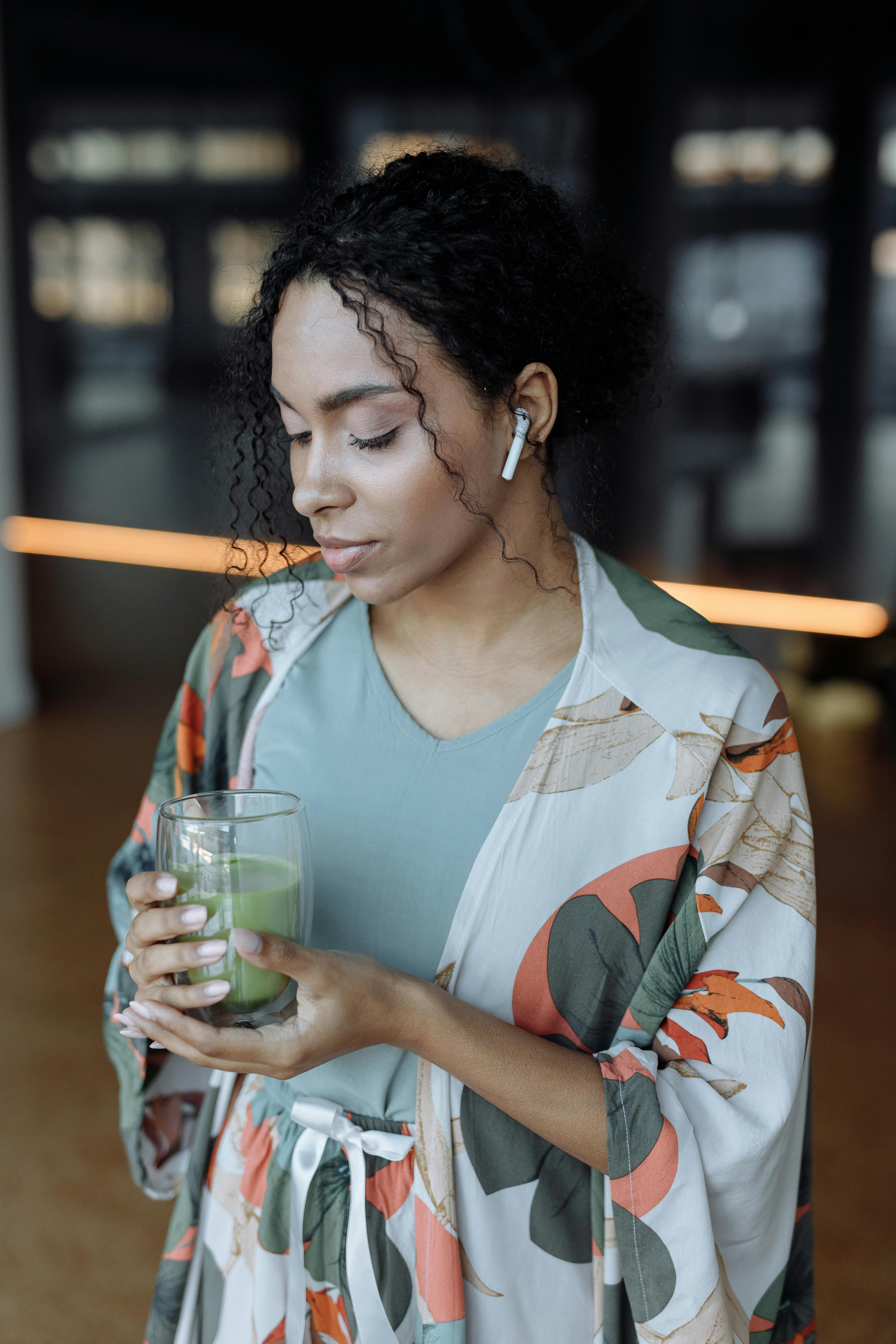 Woman in Blue and White Floral V Neck Shirt Holding Drinking Glass