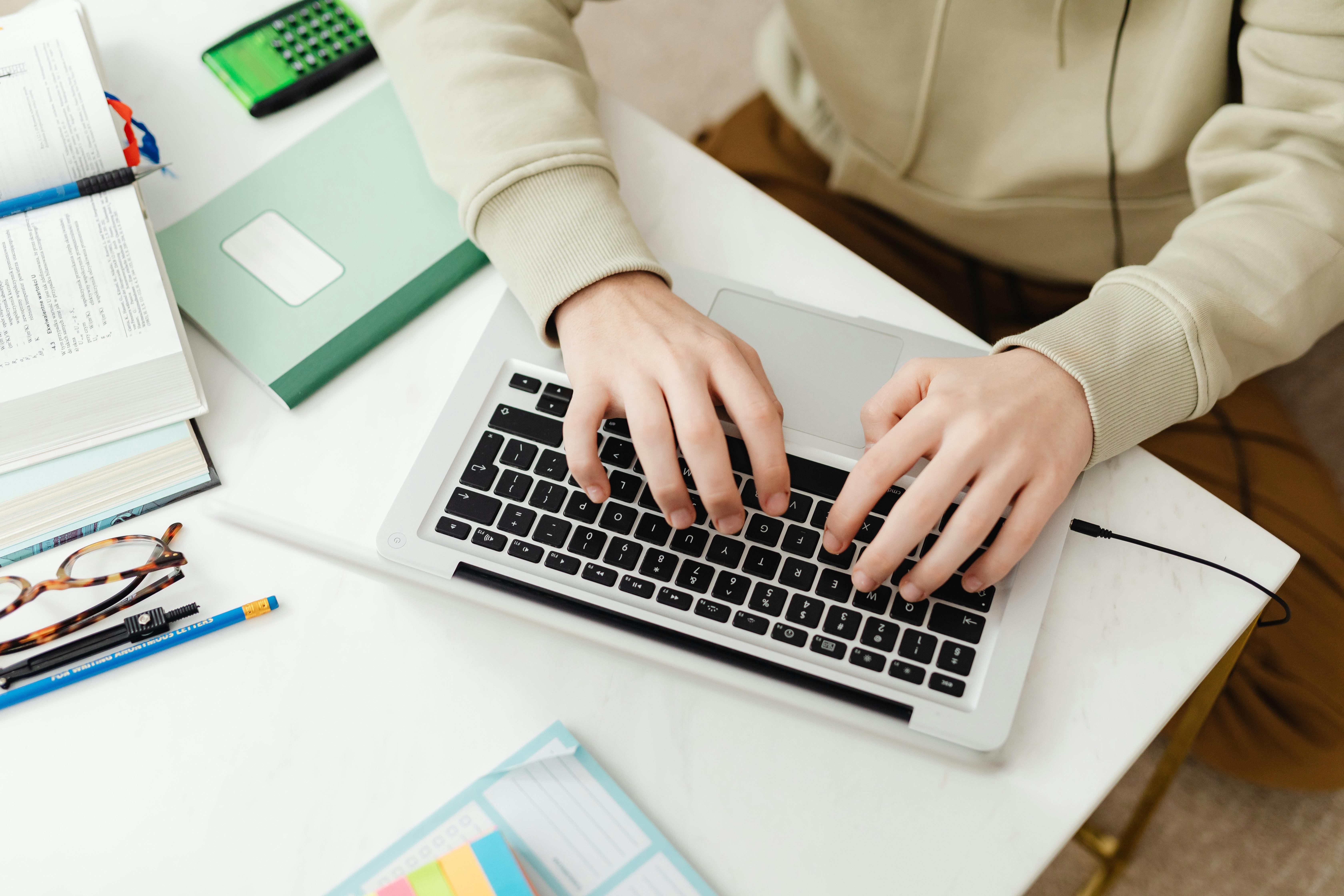 person typing on laptop studying at desk