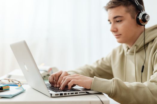 Teen using a laptop and headphones for online learning at home.