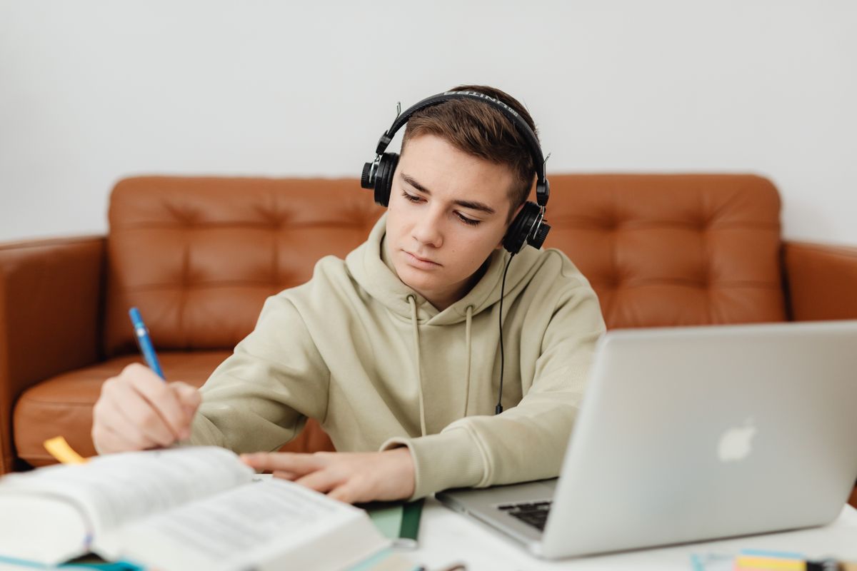 Teen student studying with a laptop and notebook while practicing focus and responsibility