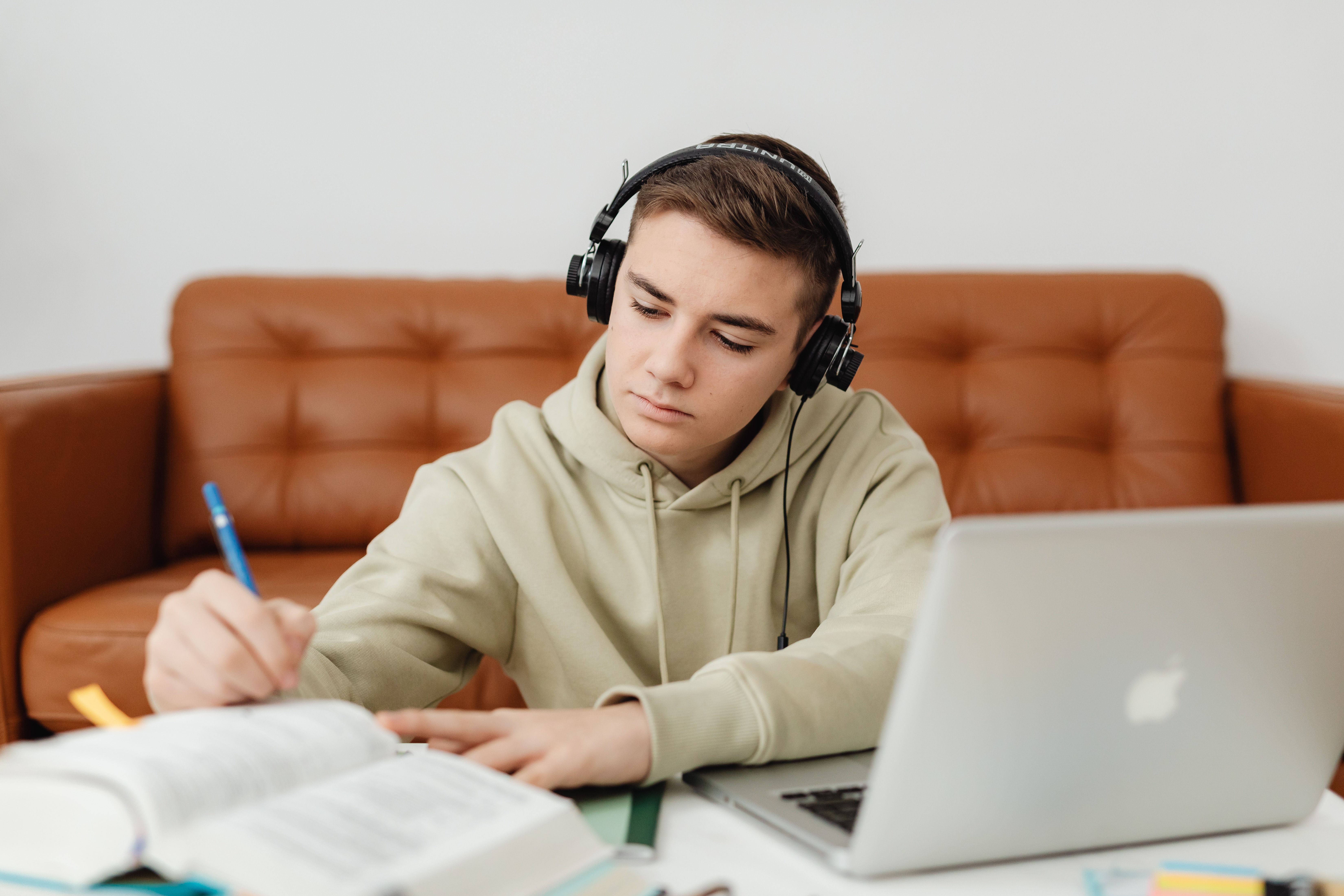 Estudiante con audífonos practicando inglés desde casa con laptop y cuaderno
