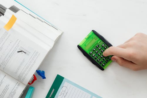 Free Person Using A Green and Black Calculator Stock Photo