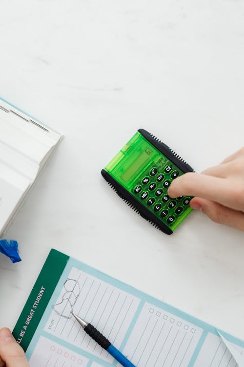 Free Person Using A Green and Black Calculator Stock Photo