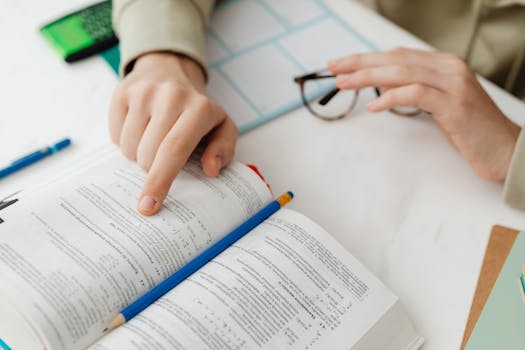 Close-up of a student studying math using a textbook and pencil at a desk indoors.