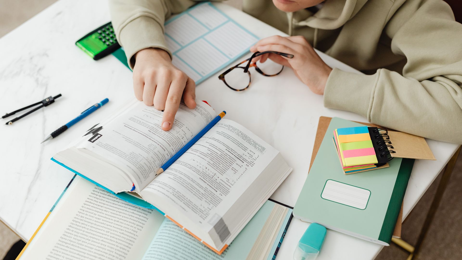 Modafinil for Overnight Exam Cramming: Unlocking Success Young student focused on studying with textbooks, calculator, and notes on a desk — modafinil for overnight exam cramming