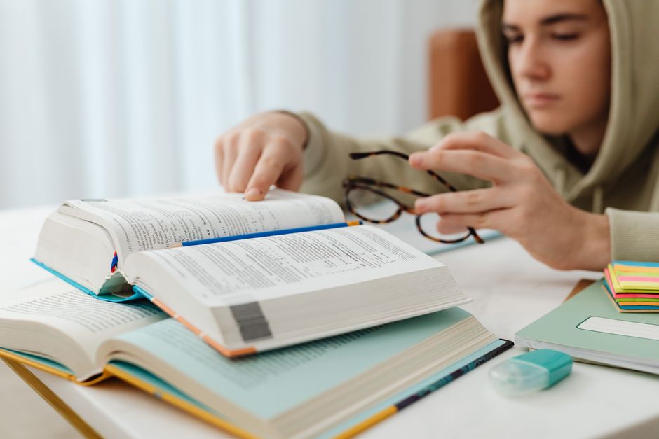 A person studying for the NMLS exam, surrounded by books and a laptop, with a focus on diligence.