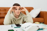 A Man Sitting Beside the Sofa while Studying