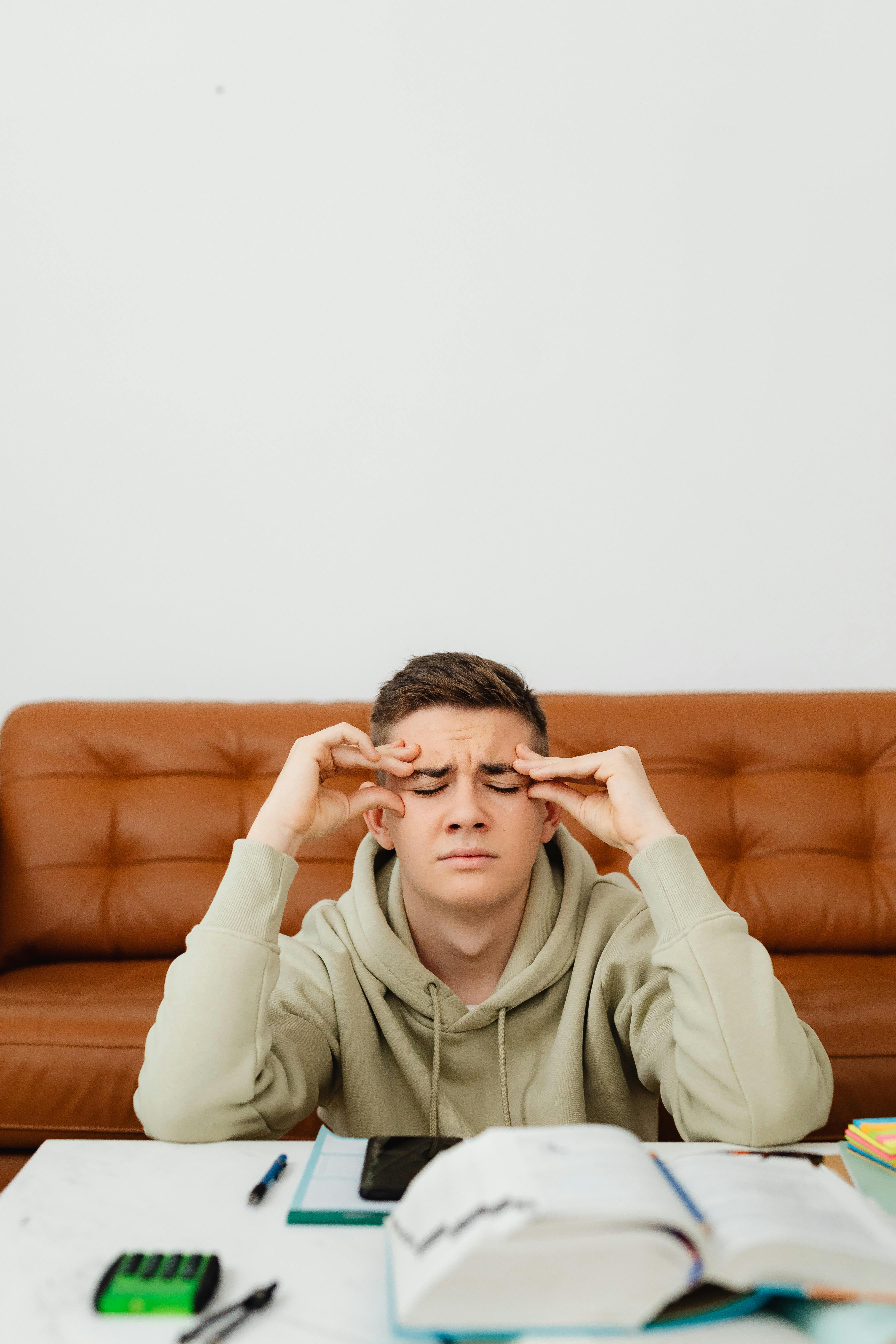 a man in green hoodie with his hands on head