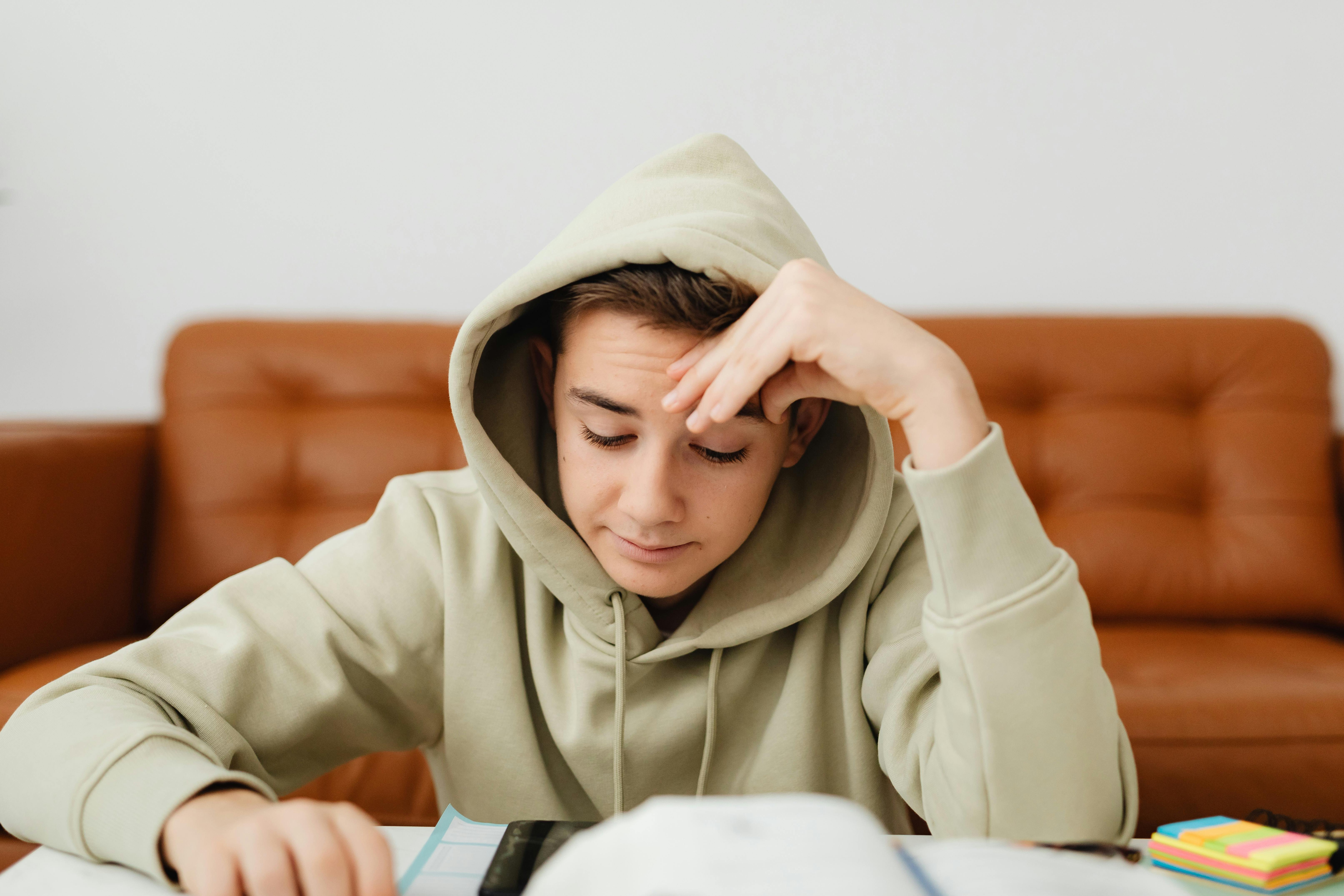 A teenager deeply focused on a notebook or book, no phone in sight, in a quiet room