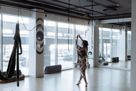 Woman practicing yoga gracefully in a modern, airy studio with natural light streaming in.