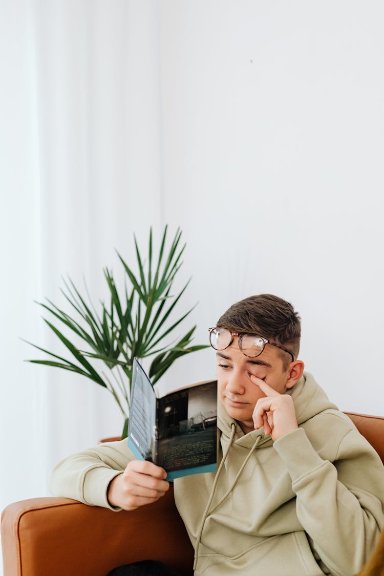 A Man Rubbing His Eye While Reading