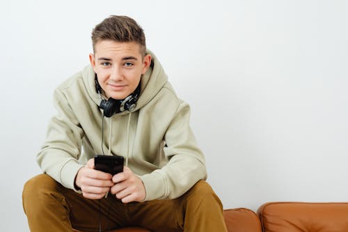 Free Fine Looking Man Wearing a Hoodie Using a Smartphone Stock Photo