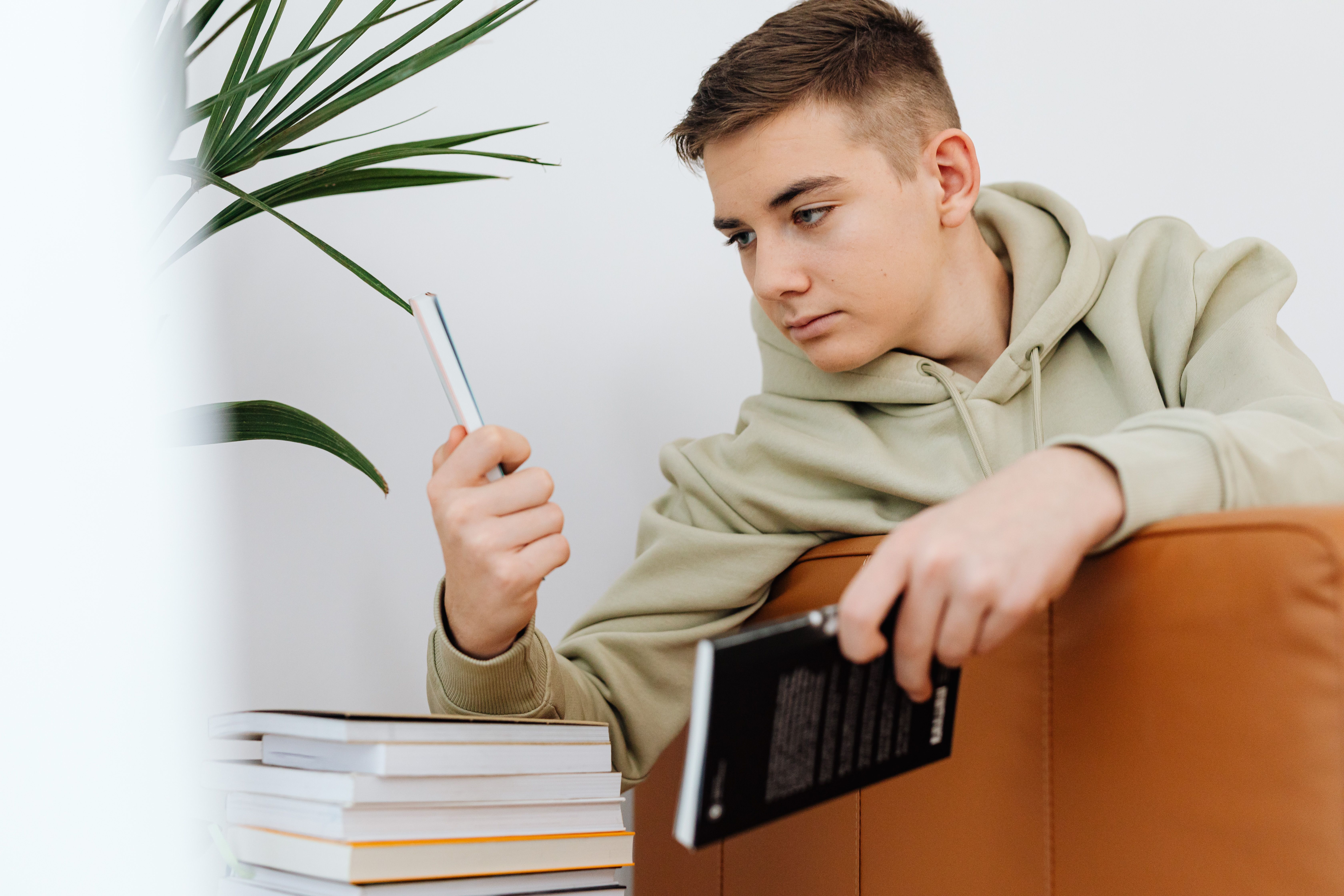 Close-Up Shot of a Boy Looking at His Cellphone while Holding a Book