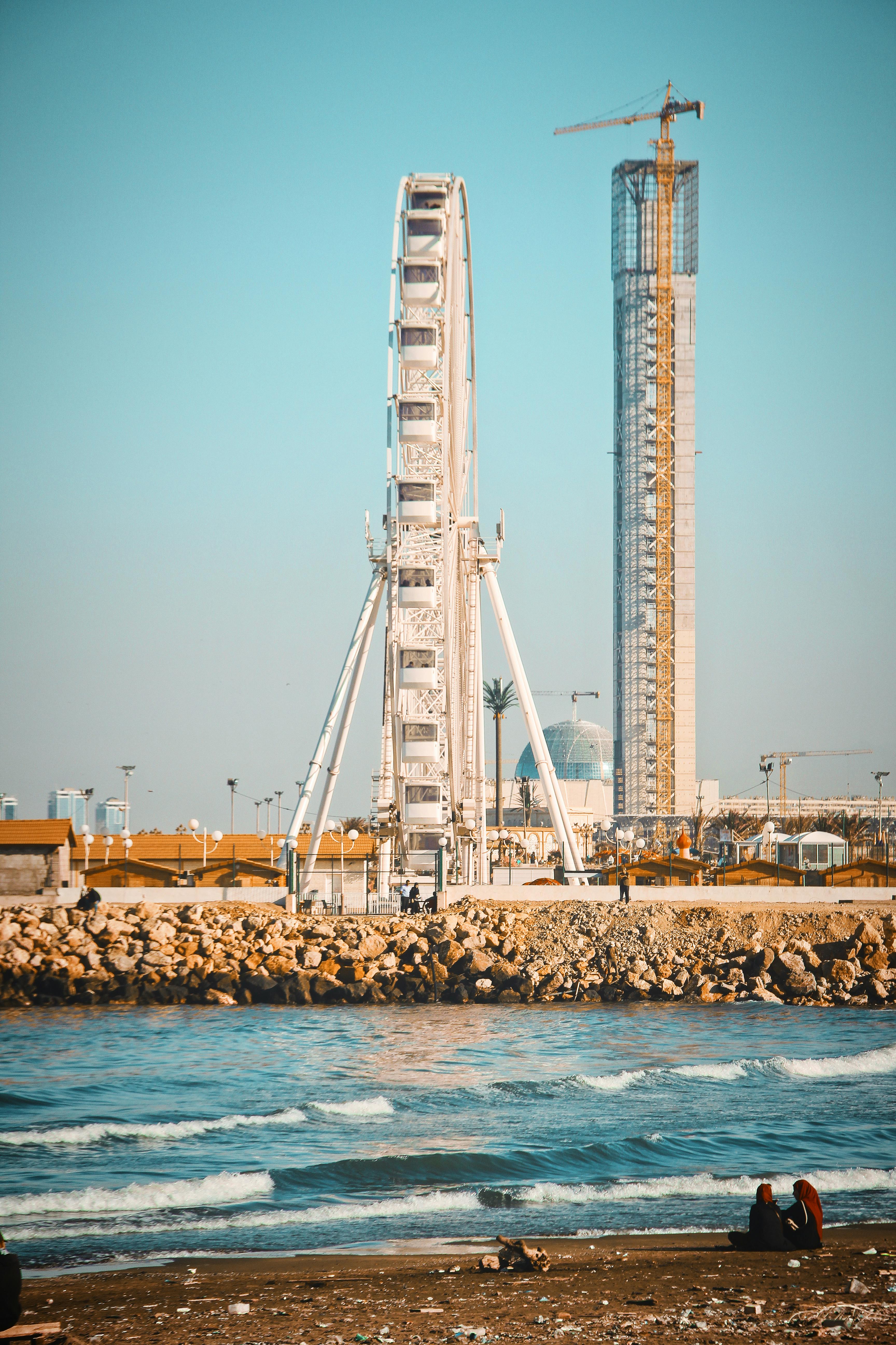 在阿尔及利亚的海岸线上，摩天轮和建筑塔矗立着，海浪拍打着海滩