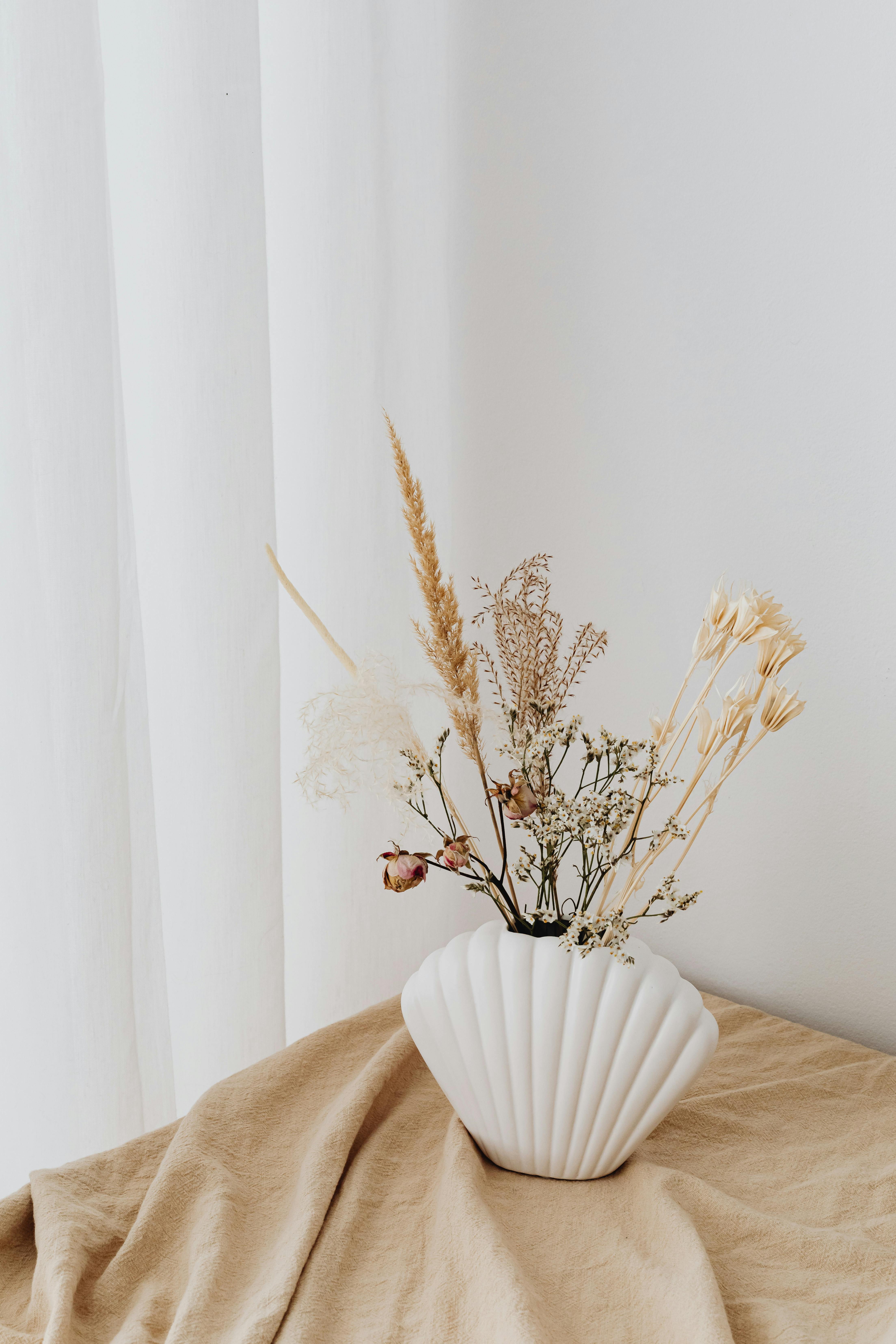 Stylish white ceramic vase filled with delicate dried flowers, perfect for modern decor.