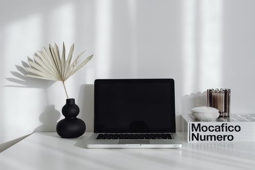 Free A minimalist desk setup featuring a laptop, a decorative vase, and books, creating a modern workspace feel. Stock Photo