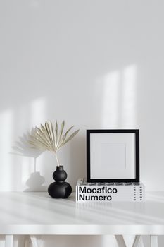 Elegant minimalist interior featuring a black frame, modern vase, and decor books.