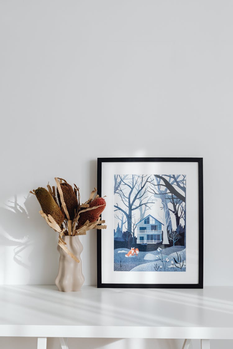 Dry Brown Plant And Blue Toned Picture On Desk