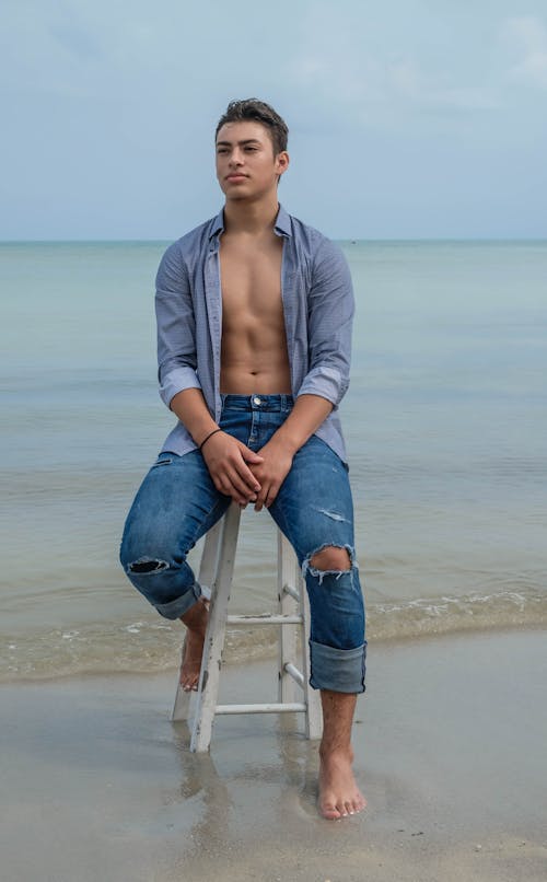 Muscular man on stool on shore near sea