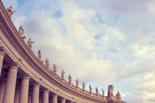 曇り空の下で人間の彫像と灰色のコンクリートの建物