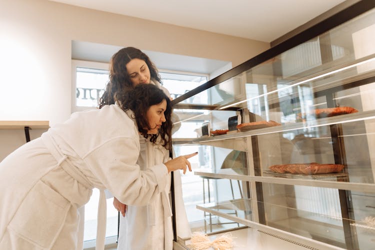 A Woman Wearing White Robe Choosing Food On A Glass Cabinet