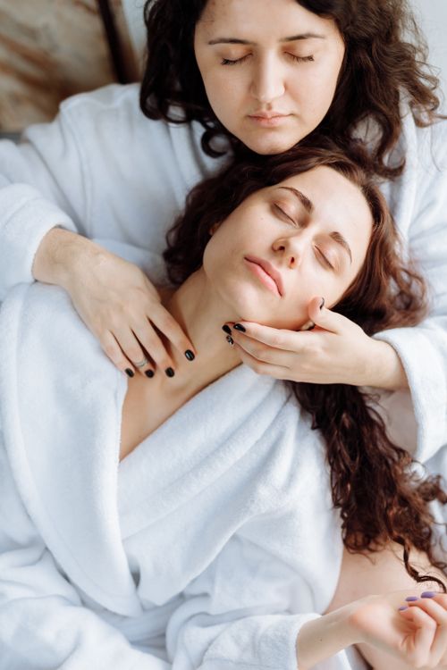 Free Two women lovingly embrace in white bathrobes, conveying warmth and intimacy. Stock Photo
