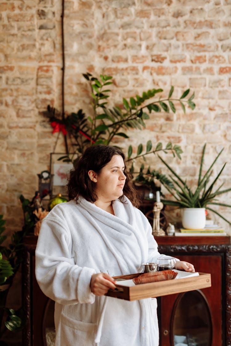 Woman In White Robe Carrying A Wooden Tray With Food