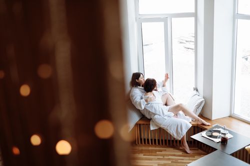 Free A cozy and intimate moment with a couple relaxing in robes by a large window, enjoying togetherness. Stock Photo