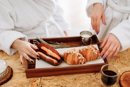 Chic breakfast setting with croissants and coffee served on a wooden tray.